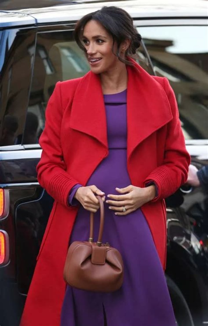 Meghan Markle Cradles Her Baby Bump In Stunning Purple Gown And Red Coat